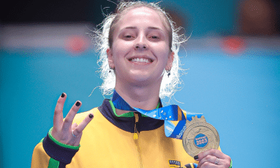 Danielle Rauen segura medalha de ouro e faz o número três com os dedos