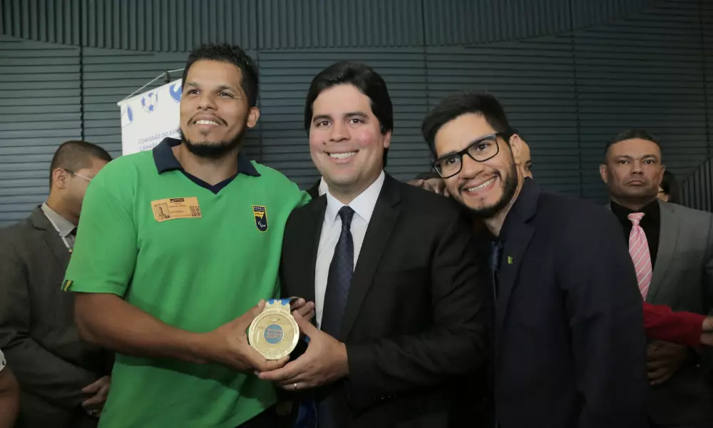 André Fufuca, ministro do Esporte, segura medalha de ouro dos Jogos Parapan-Americanos ao lado de Leomon MOreno, atleta de goalball, e do ex-atleta Yohansson Nascimento; ele anunciou reajustes no Bolsa Atleta para paralímpicos