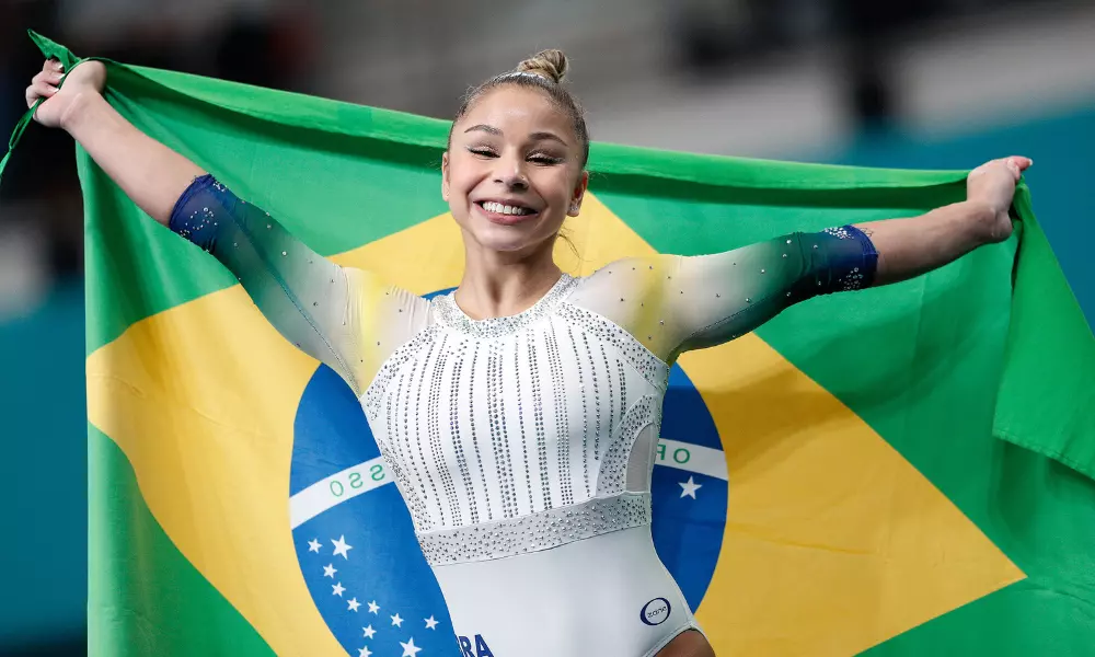 Flávia Saraiva sorri enquanto segura a bandeira do Brasil