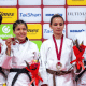Rosi Andrade está com a medalha de bronze e segura um ramo de flores e está ao lado das outras três medalhistas de sua categoria no Grand Prix de Tóquio de judô paralímpico, em frente ao backdrop do evento