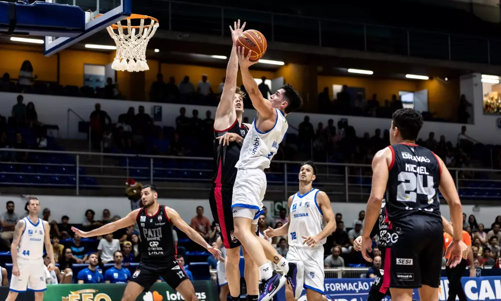 Jogador do Pato Basquete tenta bloquear arremesso do Minas em jogo do NBB