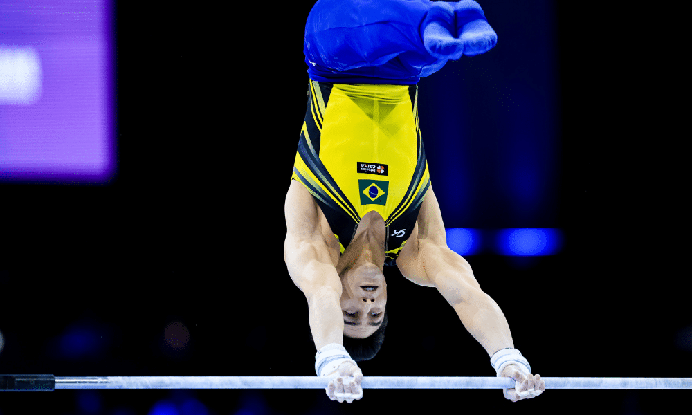 Arthur Nory de calça azul e regata amarela na barra fixa