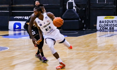 Jogador do União Corinthians com a bola enquanto é marcado por atleta do Botafogo no NBB
