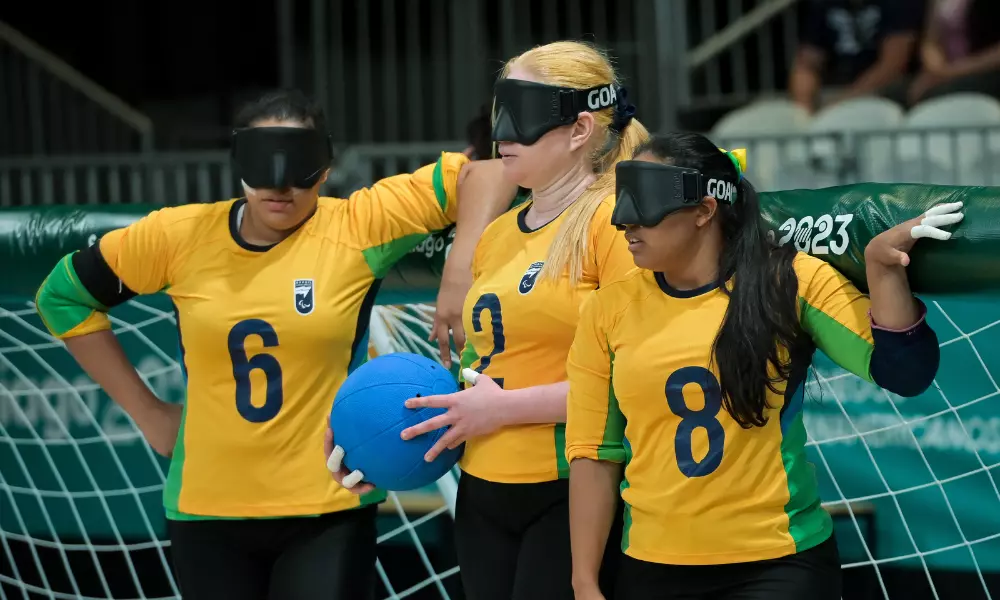 Gabriely Brito está com a bola na mão, no centro, enquanto Jessica Vitorino e Kátia Aparecida aparecem ao seu lado; o goalball feminino do Brasil garantiu vaga em Paris 2024