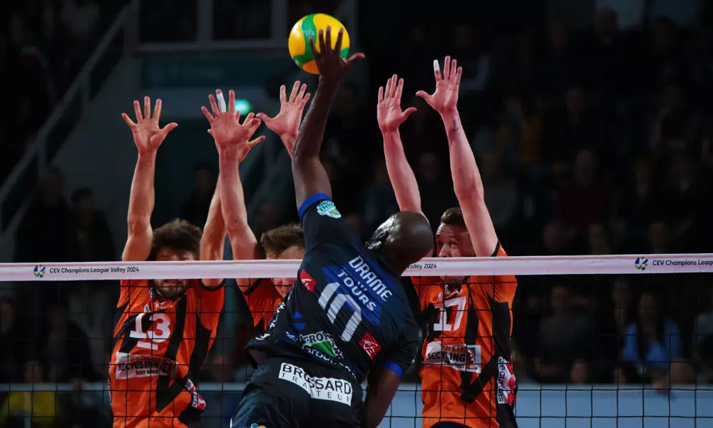 Abouba, do Tours, atacando contra bloqueio triplo do Berlin na Champions League de vôlei masculino