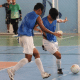 Raynã e Lucas Caetano, que vestem coletes azuis sem camisetas por baixo e calções e meiões azuis, disputam jogada durante treino em uma quadra coberta. Ao fundo, desfocados, aparecem os goleiros Matheus e Giovane. Foto: Renan Cacioli/ CBDV.