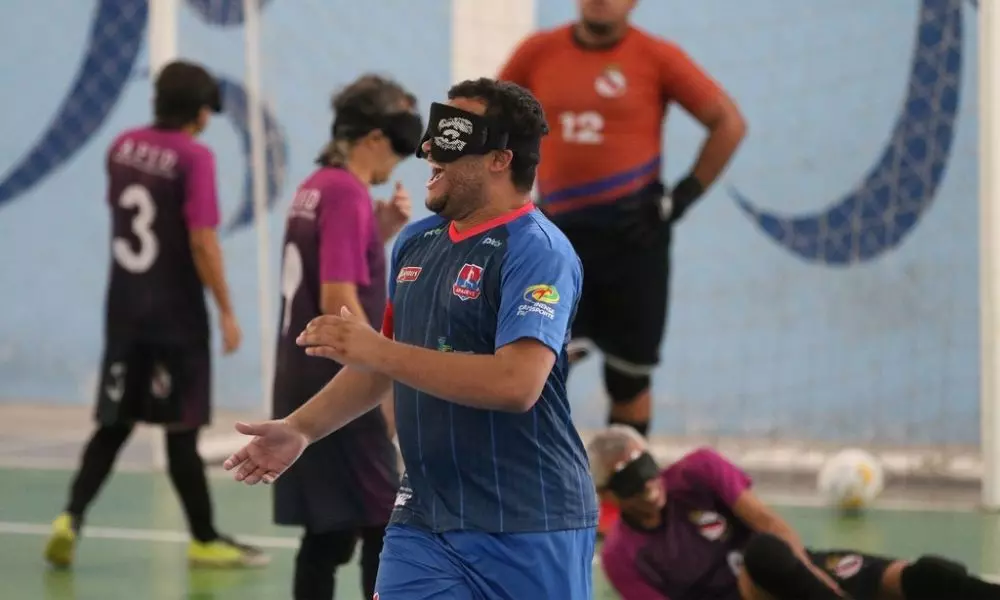Guegueu, que veste camisa azul da Apadevi, sorri enquanto comemora um de seus dois gols na vitória sobre a Apid pelo Regional Nordeste de futebol de cegos (Foto: Renan Cacioli/CBDV)