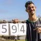 O saltador goiano Rodrigo Parreira posa para foto ao lado da placa do recorde das Américas no Open Internacional de atletismo paralímpico (Foto: Ale Cabral/CPB)