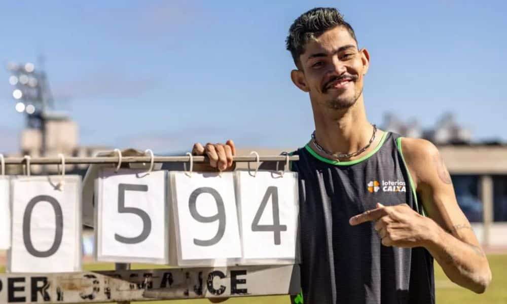 O saltador goiano Rodrigo Parreira posa para foto ao lado da placa do recorde das Américas no Open Internacional de atletismo paralímpico (Foto: Ale Cabral/CPB)