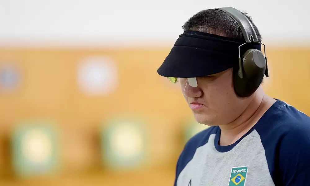 Felipe Wu, com viseira e fones de proteção, com cabeça abaixada cabisbaixo no Campeonato da Américas de tiro esportivo, em que ele não conseguiu vaga olímpica