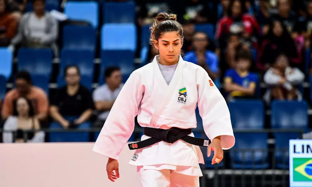 Amanda Lima, de judogi branco, olhando para baixo antes de luta no Grand Slam de Dushanbe de judô; Michel Augusto também perdeu nas oitavas