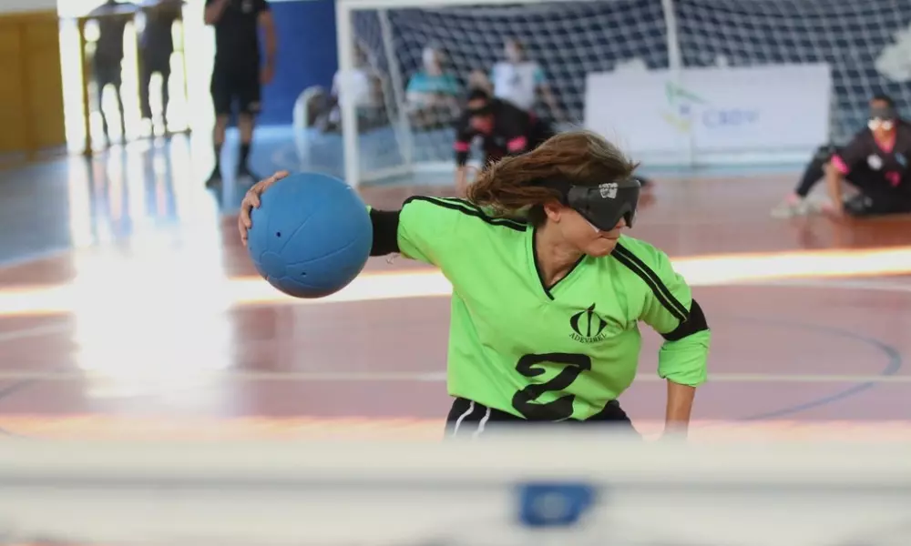 Christiane, artilheira da Adevibel e do Regional, é fotograda por trás do gol da equipe mineira no instante em que faz o giro do arremesso, com o braço direito segurando a bola. Ela veste camisa verde de manga longa com o número 2 em preto na altura do peito. Foto: Renan Cacioli/ CBDV.