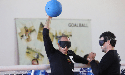 Jeferson, da Urece, segura a bola no alto, com o braço direito bem erguido, enquanto apoia a mão esquerda na trave. Ao seu lado, Felippe se aproxima. Foto: Renan Cacioli/ CBDV
