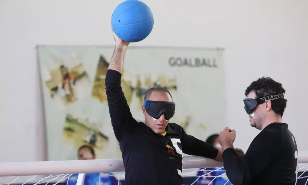 Jeferson, da Urece, segura a bola no alto, com o braço direito bem erguido, enquanto apoia a mão esquerda na trave. Ao seu lado, Felippe se aproxima. Foto: Renan Cacioli/ CBDV