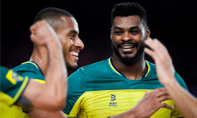 Lucarelli e Isac sorriem durante partida da Liga das Nações de vôlei masculino, a VNL. Eles ficaram fora do duelo contra a Polônia
