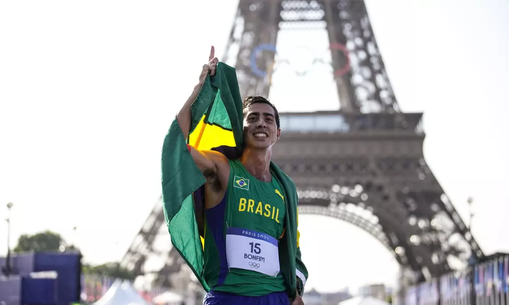 Caio Bonfim com a bandeira do Brasil em frente a Torre Eiffel na marcha atlética dos Jogos Olímpicos de Paris-2024