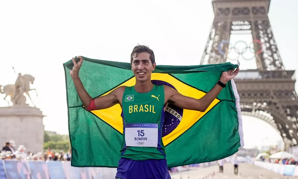 Caio Bonfim com bandeira do Brasil em frente a Torre Eiffel