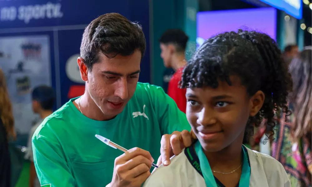 Caio Bonfim autografando uniforme de menina durante a COB Expo