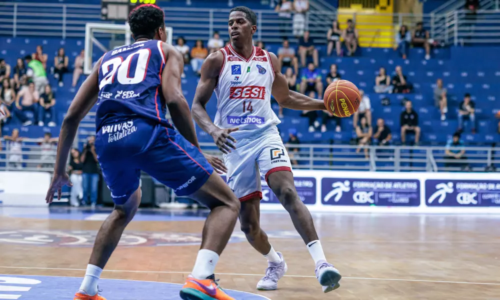 Georginho de Paula conduz a bola no jogo entre Sesi Franca e Fortaleza no NBB. Ele veste shorts e camisa brancos e carrega a bola com a mão esquerda