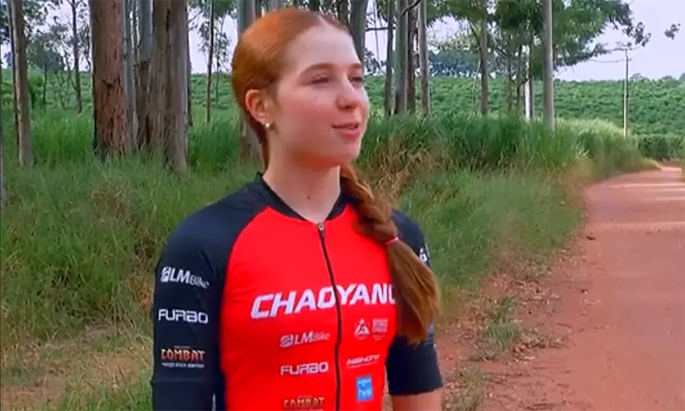 Na imagem, ciclista Ana Laura posicionada ao lado da estrada de terra.