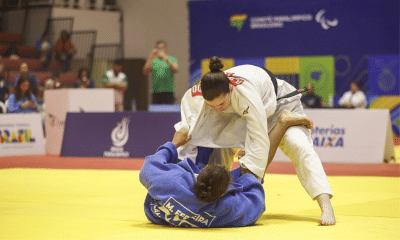 Alana Maldonado está de kimono branco, em pé, inclinada para frente, enquanto segura a outra atleta, que está de kimono azul e deitada de costas no tatame.