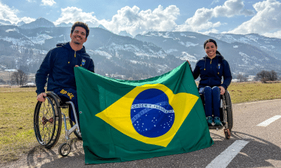 Esquiadores Cristian Ribera e Aline Rocha seguram a bandeira do Brasil em Predazzo, na Itália | Foto: Alessandra Cabral/ CPB