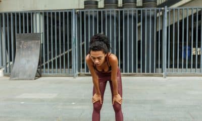 Pessoa cansada durante treino, olhando para o chão ou apoiando as mãos nos joelhos