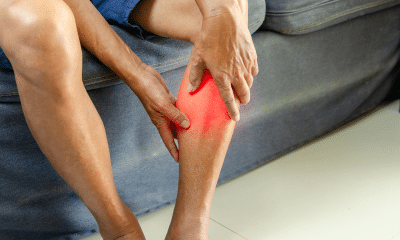 Pessoa segurando a panturrilha durante atividade física, com expressão de desconforto, evidenciando dor localizada.