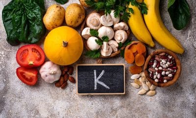 Mesa com banana, abacate, batata-doce, feijão, folhas verdes e copo de água de coco, em composição colorida.